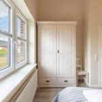 Schlafzimmer mit Fenster, Kleiderschrank und Tür.