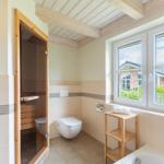 Badezimmer mit Sauna, Toilette, Badewanne und Fenster mit Blick.