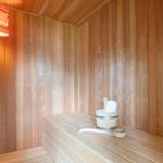 Sauna mit Holzwand, Sitzbank und Eimer mit Handtuch.