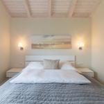 Schlafzimmer mit Bett, Nachttischen und Wandbild.