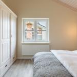 Schlafzimmer mit Doppelbett, Kleiderschrank und Fenster zur Außenseite.