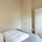 Schlafzimmer mit Bett, Kleiderschrank und Tür.