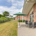 Terrasse mit Tisch, Stühlen und grünem Sonnenschirm neben Haus mit Backsteinmauer.