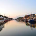 Hafen mit Booten und beleuchteten Gebäuden am Abend