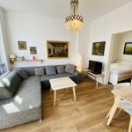 Wohn- und Essbereich mit Sofa, Tisch und TV. Schlafzimmer mit Bett sichtbar.