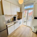 Küche mit Kühlschrank, Spüle und Fenster zur Terrasse.