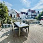 Terrasse mit Tisch und Stühlen, Blick auf Wohnhäuser und Bäume.