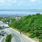 Meerfront mit Strand, Wald und Parkplatz. Blick auf Küstenstraße mit Booten und Fahrrädern.