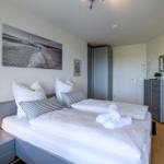 Schlafzimmer mit Doppelbett, Kleiderschrank und Spiegelschrank.