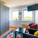 Zimmer mit Kleiderschrank, Sitzgelegenheit und TV. Fenster mit Blick auf Grün.