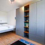 Schlafzimmer mit Doppelbett und Kleiderschrank mit Regalen.