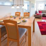 Essbereich mit Tisch und Stühlen. Wohnzimmer mit Sofa und Teppich.