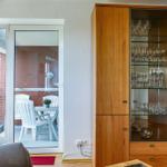 Wohnzimmer mit Balkon, Glasvitrine und Fernseher