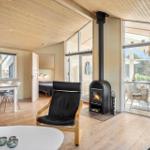 Wohnraum mit Kamin, Essbereich und Terrasse. Holzdecke und -boden.