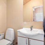 Badezimmer mit Waschbecken, Spiegel und Toilette. Handtuch hängt an der Tür.