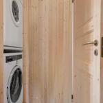 Wäscherei mit Waschmaschine und Trockner. Tür führt in Bad mit Dusche.