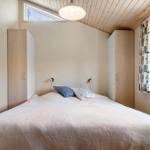 Schlafzimmer mit Bett, Kleiderschränken und Fenstern.