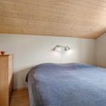 Schlafzimmer mit Holzdecke, Bett und Kleiderschrank. Fenster mit Blick nach draußen.