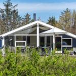 Ein Haus mit blauer Fassade und großem Glasbereich. Außenbereich mit Tisch, Stühlen und Sonnenschirm.