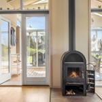 Innenraum mit Kaminofen, Terrasse und Sitzbereich. Durchgänge zu Außenbereich.