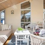 Ein Wohnbereich mit Sofa, Stühlen und Tisch. Große Fenster und Holzdecke.