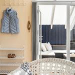 Ein Raum mit Schuhregal, Jacke und Blick auf eine Terrasse mit Sitzmöbeln.