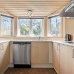 Küche mit Holzdecke, Fenstern und moderner Geräteausstattung.