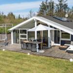 Haus mit Terrasse, Grillplatz und Garten. Weiße Sonnenschirme und Sitzgelegenheiten.