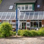 Ein Haus mit Glasveranda und Sitzgelegenheiten im Vorgarten.