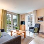 Wohnzimmer mit Sofa, Sessel, Couchtisch und Fenstern zur Terrasse.