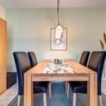 Esszimmer mit Holztisch, sechs Stühlen und Wanddekoration.