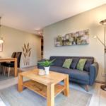 Wohn- und Essbereich mit Sofa, Tisch und Wandbild.