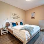 Schlafzimmer mit Doppelbett, Wanddekoration und Terrassentür.