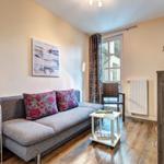 Ein Wohnzimmer mit Sofa, Tisch und Fenster. An der Wand hängt ein Bild.