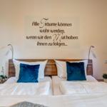 Doppelbett mit blauen Kissen und Wanddekoration.