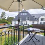 Balcony with table, chair, and umbrella overlooking a residential area.