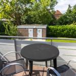 Terrasse mit Tisch und zwei Stühlen. Blick auf grüne Bäume und einen Garten.