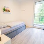 Schlafzimmer mit Bett, Nachttisch und Balkontür.