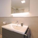 Badezimmer mit Waschbecken, Spiegel und Dusche.