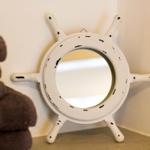 Spiegel im Stil eines Schiffsruders mit weißen Armaturen und dunklen Flecken.