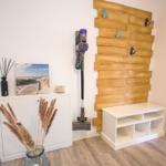 Raum mit Holzwand, Staubsauger, Schrank und Vase mit Pflanzen.