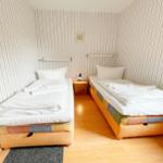 Zwei Einzelbetten mit weißen Bettwäschen und bunten Matratzenbezügen.