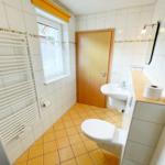 Badezimmer mit Toilette, Waschbecken und Heizkörper an der Wand.