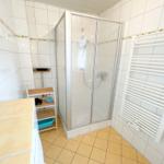 Badezimmer mit Dusche, Heizkörper und Waschbecken