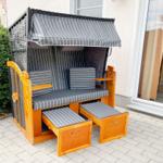 Hochwertiger Strandkorb mit Schutzdach und Sitzbänken auf Terrasse.
