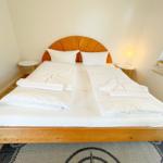 Schlafzimmer mit Doppelbett, Holzboden und Fenster.