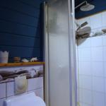 Badezimmer mit Dusche, Toilette und maritimen Dekorationen.