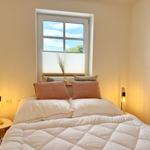 Doppelbett mit weißen Bettwäsche und zwei Nachttische mit Lampen.