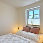 Ein Schlafzimmer mit Bett, Fenster und Nachttischlampen.