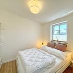 Schlafzimmer mit Bett, Kleiderschrank und Fenster.